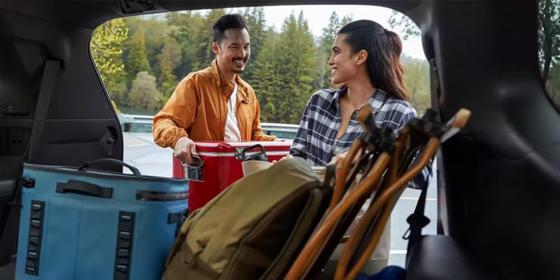 . Una persona y otra persona de pie en un coche con equipaje